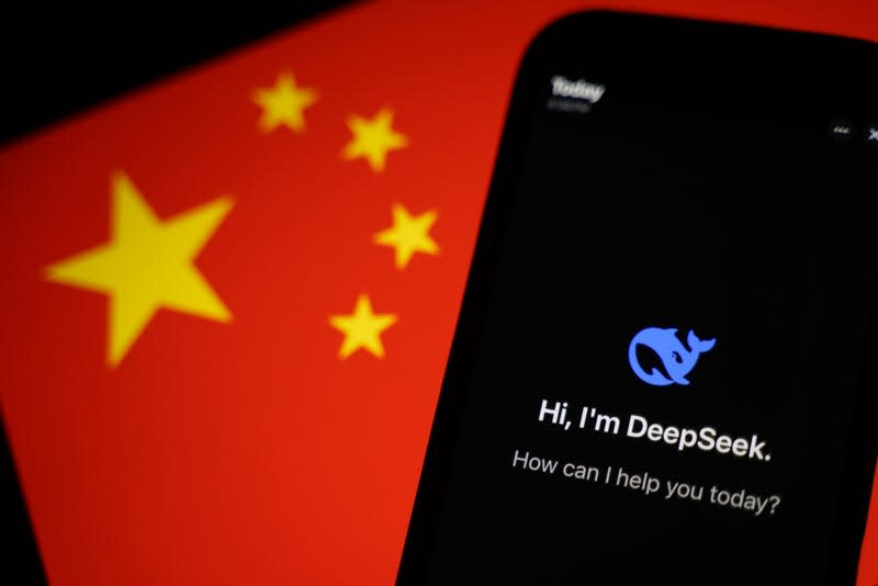 Приложение DeepSeek, отображаемое на смартфоне перед китайским флагом. Иллюстратор: Энтони Кванн (изображение Getty Images).