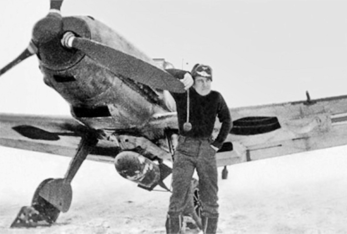 Командир 5-го штаффеля эскадры JG 5 обер-лейтенант Франц Ментцель фотографируется возле своего истребителя-бомбардировщика "Мессершмитт" Bf-109E-7/B, под фюзеляжем которого подвешена 250-кг бомба. Финляндия, аэродром Петсамо, начало февраля 1942 года.