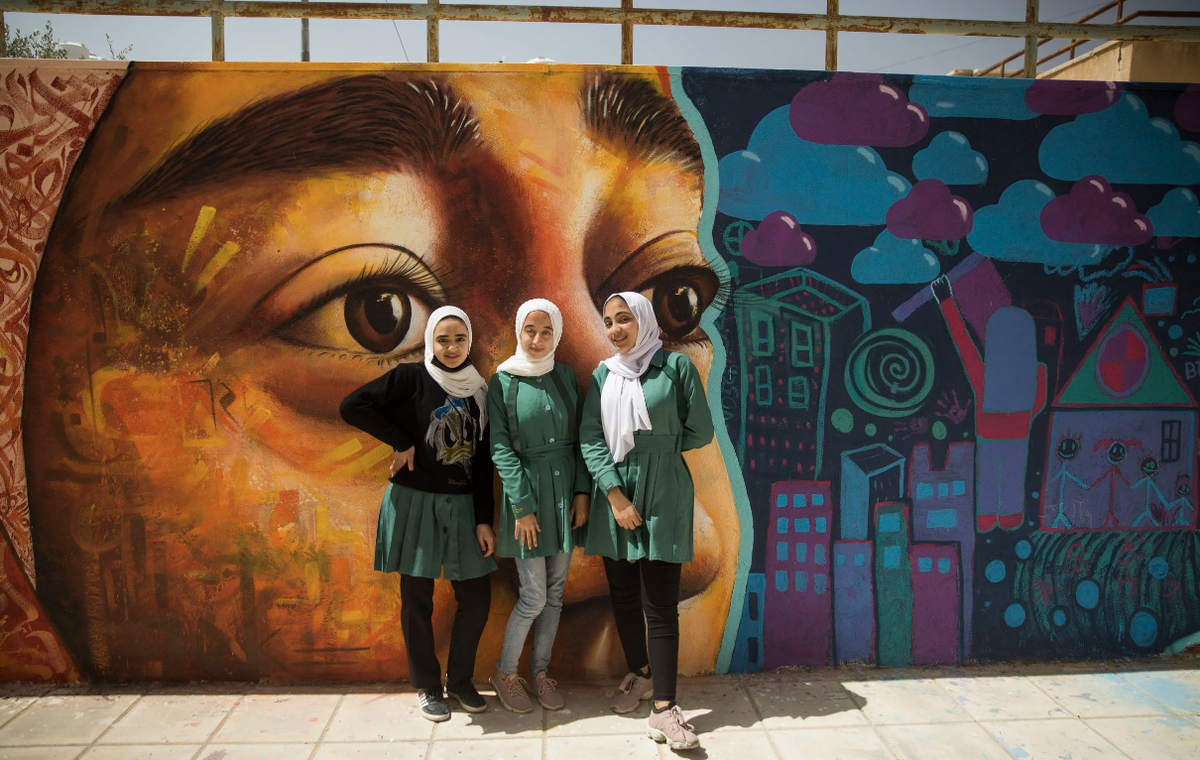 Сирийские студенты в Иордании позируют перед муралом, который они помогали создавать и раскрашивать. ©Artolution / www.artolution.org