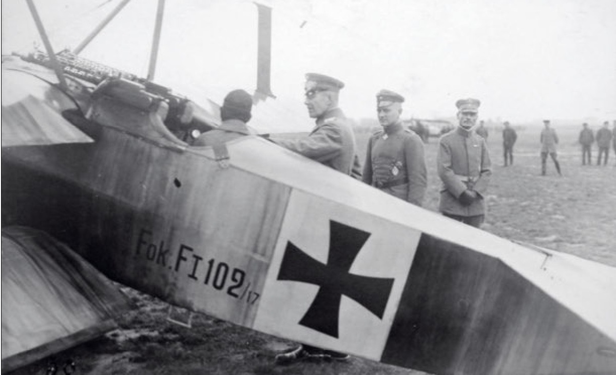 командир I-й истребительной эскадры Манфред фон Рихтгофен (второй справа) представляет нескольким официальным лицам, которые посетили его эскадру, предсерийный истребитель Fokker F.I 102/17; 31 августа 1917 года. Энтони Фоккер находится в кабине самолета и дает объяснения генералу Фрицу фон Лоссбергу, начальнику штаба 4-й армии. За фон Рихтгофеном находится лейтенант ас 6-й эскадрильи Георг Адам (21 победа, погиб в бою 15 ноября 1917 года). Снимок DR и из коллекции Давида Мешена