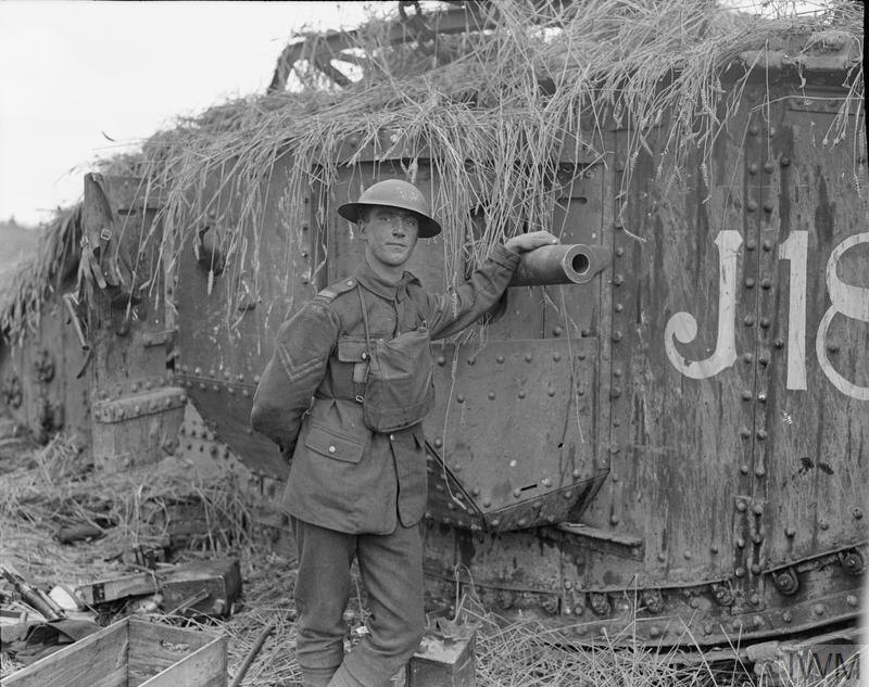 Капрал танкового корпуса стоит рядом с замаскированным танком Mark V «J18» 10-го батальона на кукурузном поле близ Альбера, 9 августа 1918 года.
