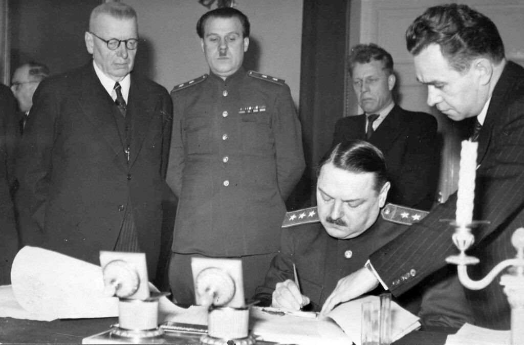 Товарищ Жданов подписывает соглашение о репарациях в декабре 1944 года. Слева – Юхо Паасикиви. Фото из сети интернет