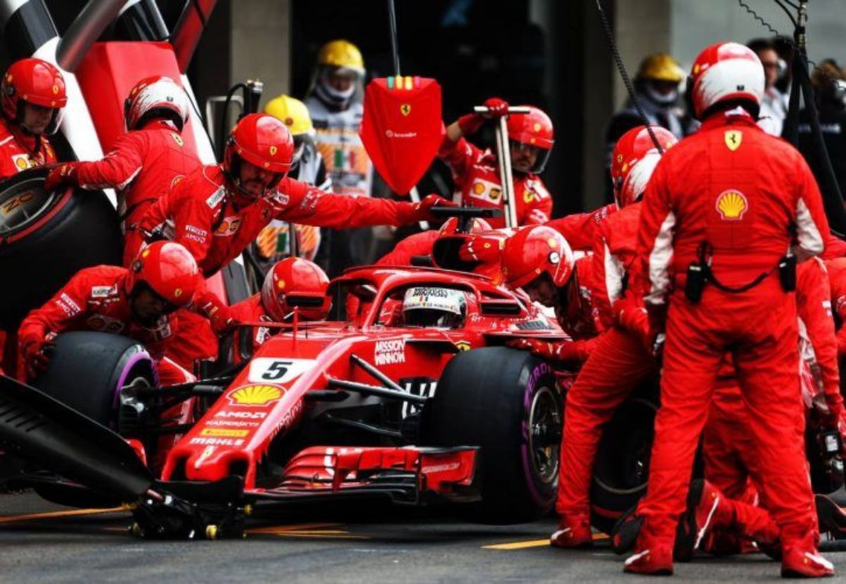 Команда Ferrari Формулы-1 проводит быструю замену шин во время пит-стопа, демонстрируя слаженную командную работу и точность.