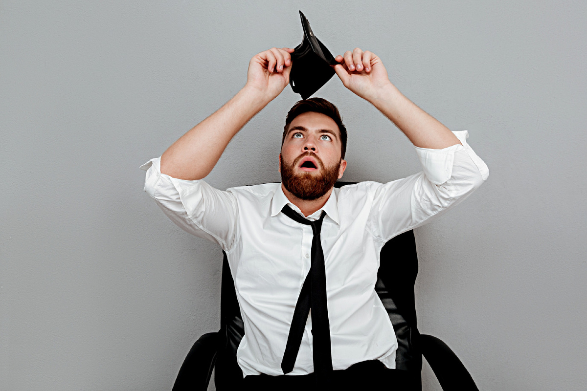 Человек смотрит в пустой кошелёк