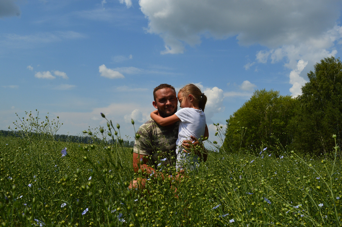 Фермер вместе с младшей дочке на своём поле льна