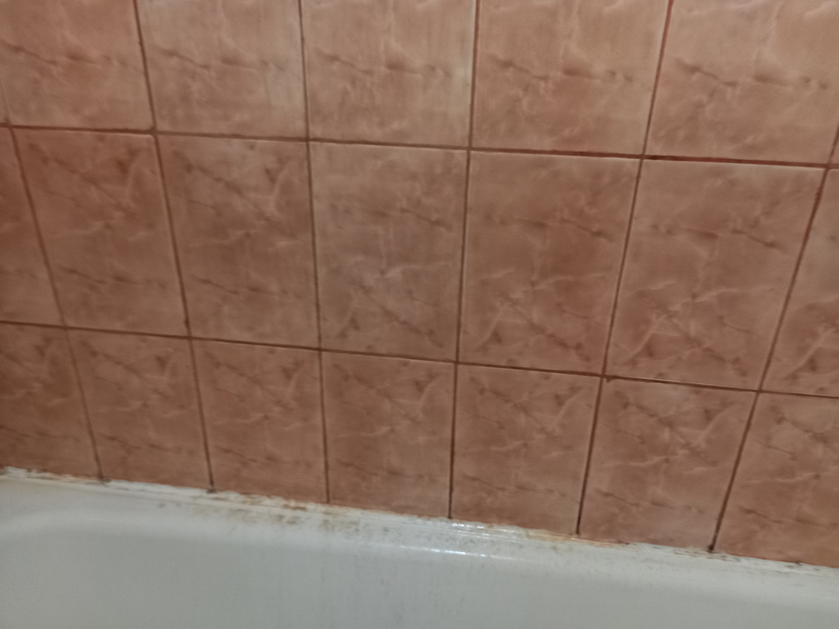 На фото оттенки немного искажены, но видно разницу между верхним рядом и остальной плиткой. И грязь, которая стекает на край ванны. Фото автора.