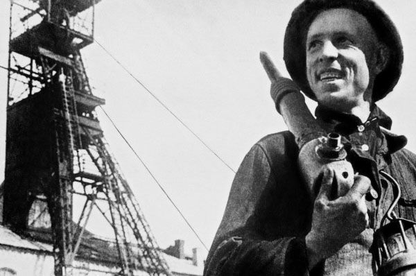 Шахтёр Алексей Стаханов с отбойным молотком на фоне копра шахты Центральная-Ирмино, 1938 год. Источник изображения: сайт aif.ru