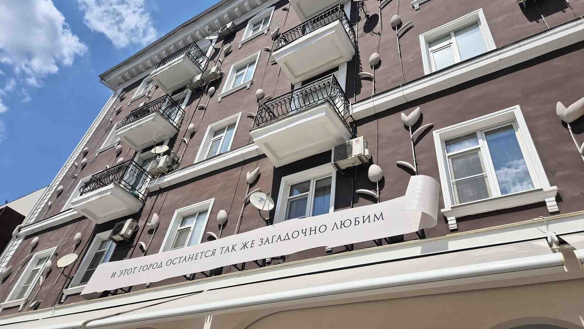 Когда город действительно любим… Фасад дома украшен цветами и цитатой из песни