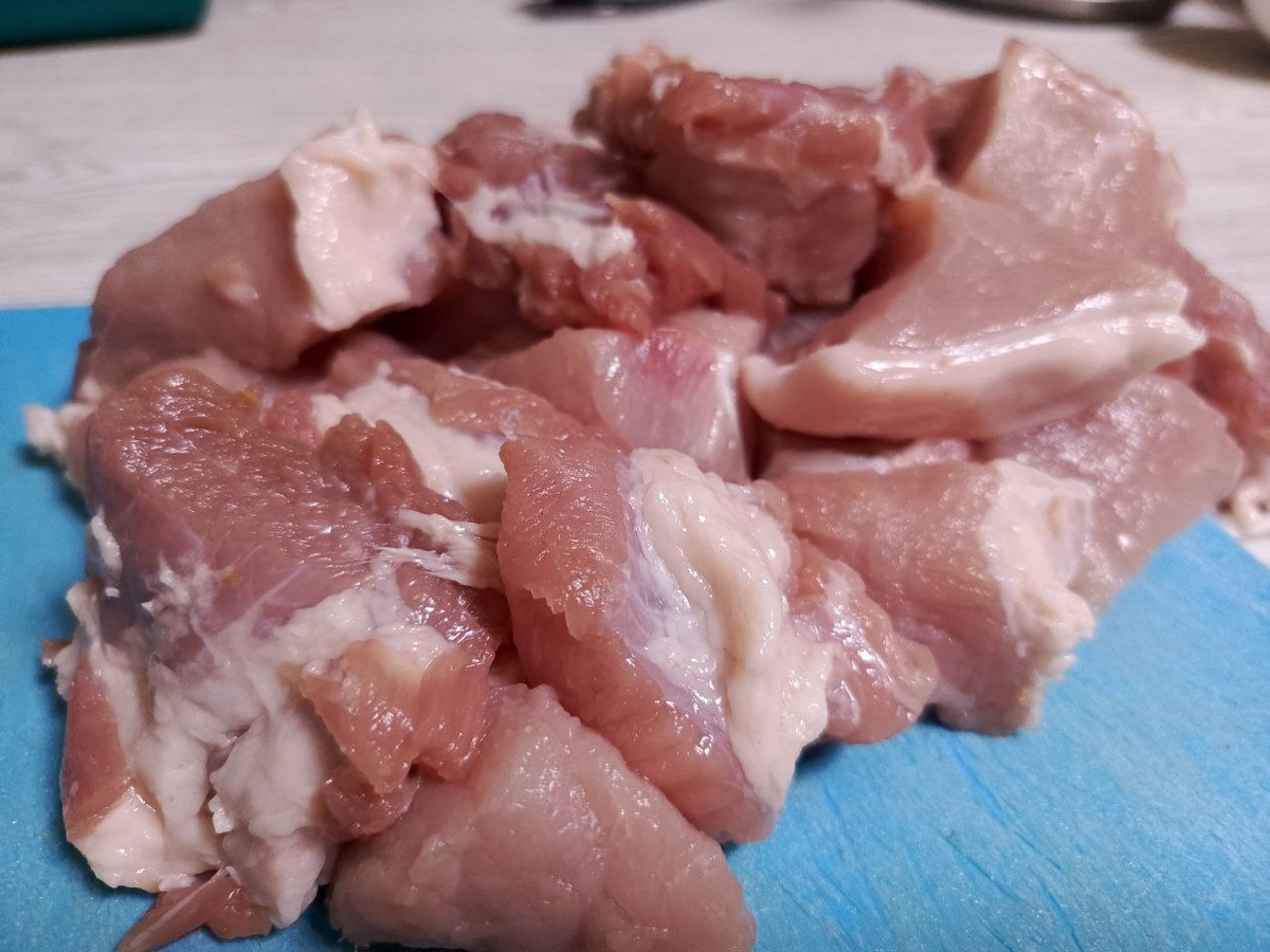 Нарежьте ломтиками средних размеров свинину. При покупке вырезки старайтесь отдавать предпочтение мясу с небольшой прослойкой жира.