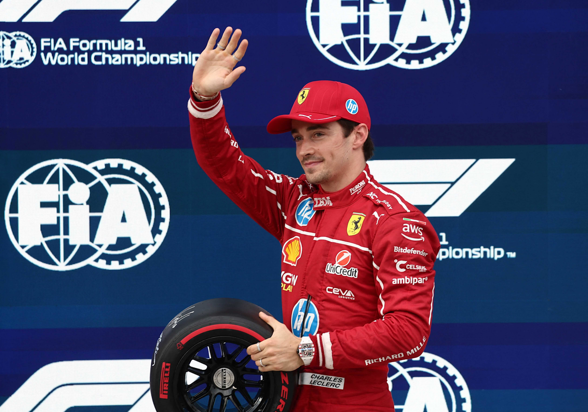 Шарль Леклер в гоночном комбинезоне Ferrari празднует поул-позицию на Гран-при Венгрии Формулы-1 2025 года с официальной шиной Формулы-1 в руке.