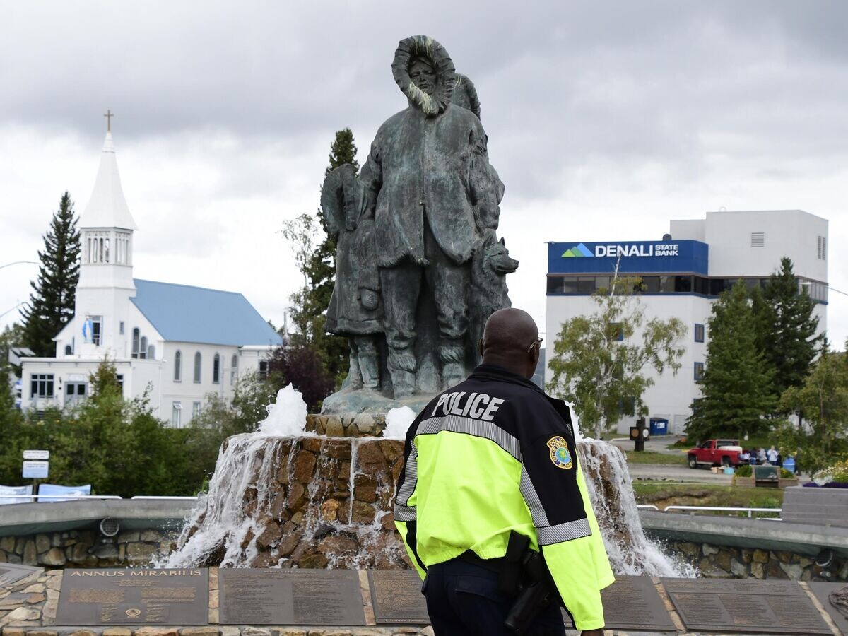    Сотрудник полиции у памятника первым поселенцам Аляски на набережной Чены и площади Голден Харт в городе Фэрбанкс на Аляске© РИА Новости / Алексей Алексеев