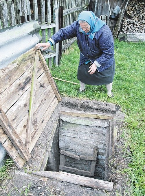 Девяностолетняя вдова Павла Максимовича Барана Любовь Ивановна показывает вход в партизанскую землянку в д. Байки. 
