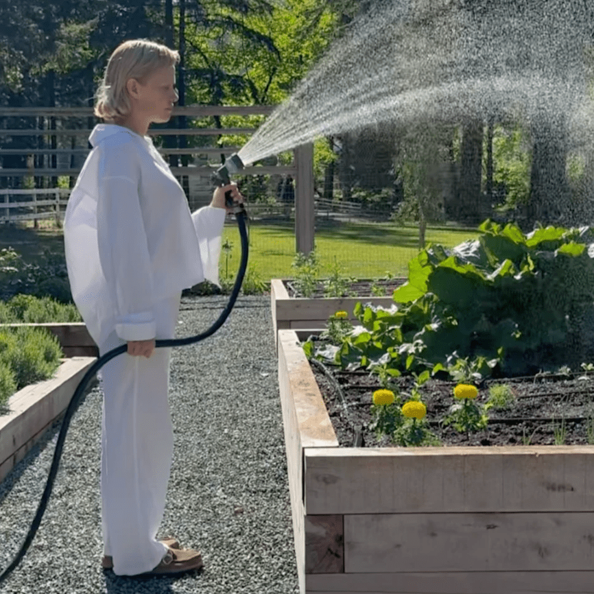 Высокие короба из грубого бруса держат форму грядок и тепло, а между ними - шуршащая гравийная тропа, по которой удобно пройти с лейкой, не таща грязь в дом. В этом кадре нет «показной» декоративности - только честная геометрия огорода, тишина хвойного леса вокруг и маленький бытовой ритуал