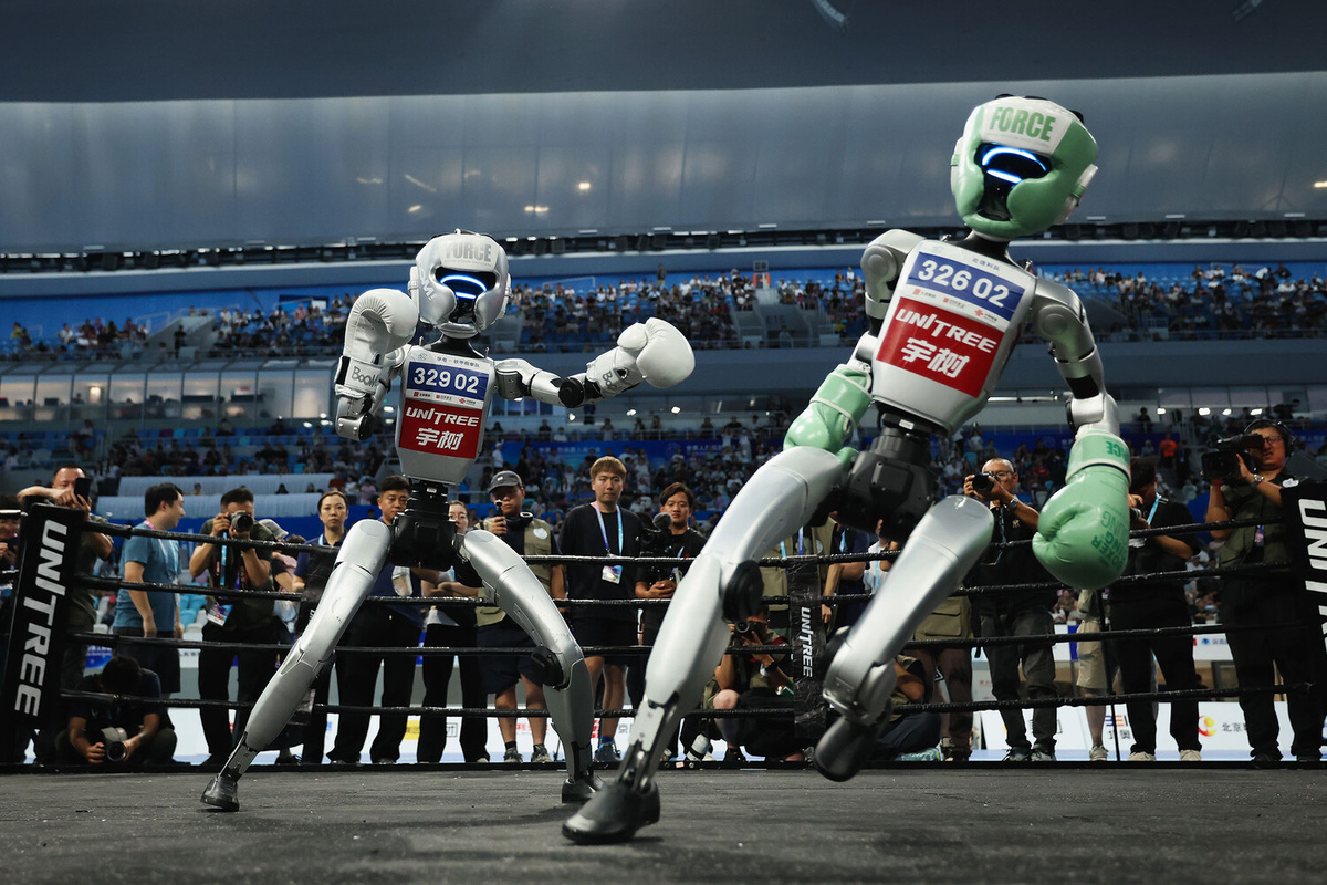Роботы-гуманоиды сражаются во время матча по кикбоксингу на первых Всемирных играх гуманоидных роботов на Национальной арене конькобежного спорта в Пекине, 16 августа 2025 года ©Lintao Zhang/Getty Images  📷