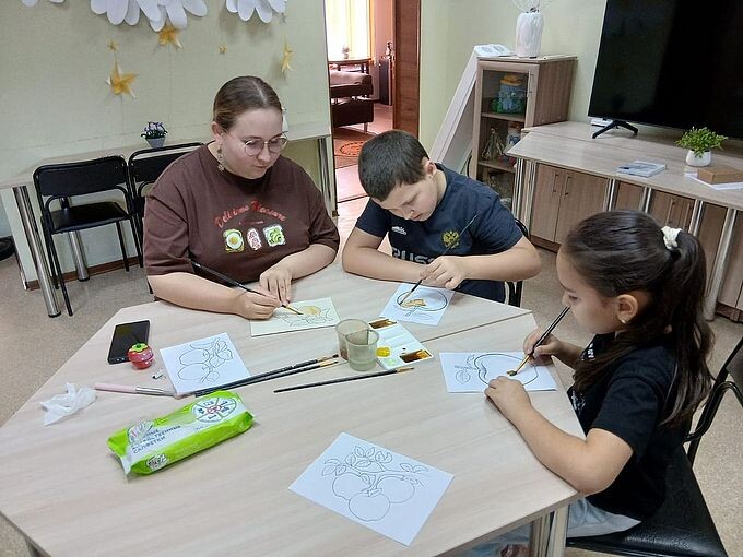 Дудникова Юлия Александровна показывает мальчику и девочке как рисовать кофе