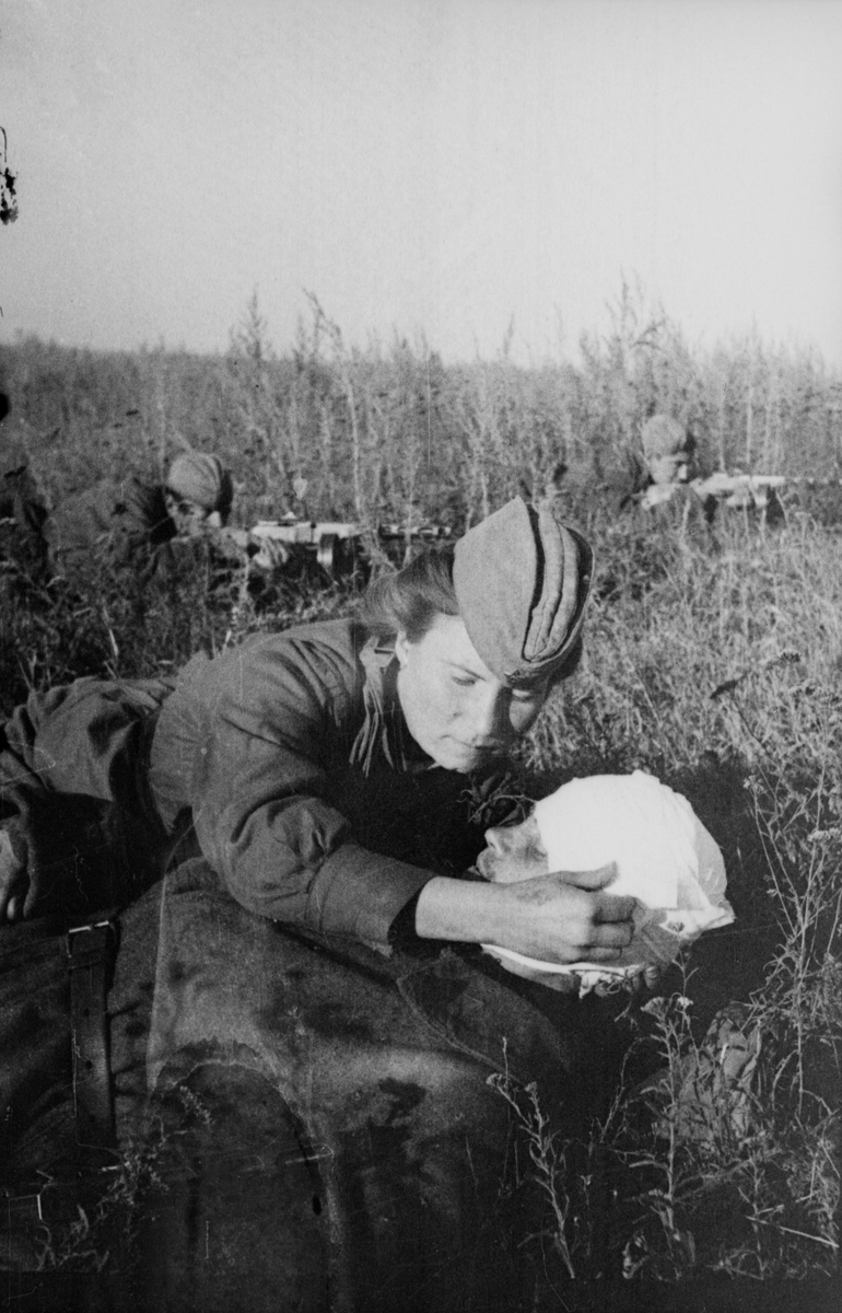 1-я армия, 34 корпус, 152 дивизия. Гвардии старший лейтенант медицинской службы Ираида Степанова перевязывает голову лежащему рядом бойцу. Ландер О. 1943 г.