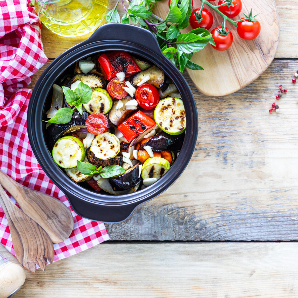    Grilled vegetables in a black ceramic pan on a wooden background. The concept of proper nutrition. Top view Журналист