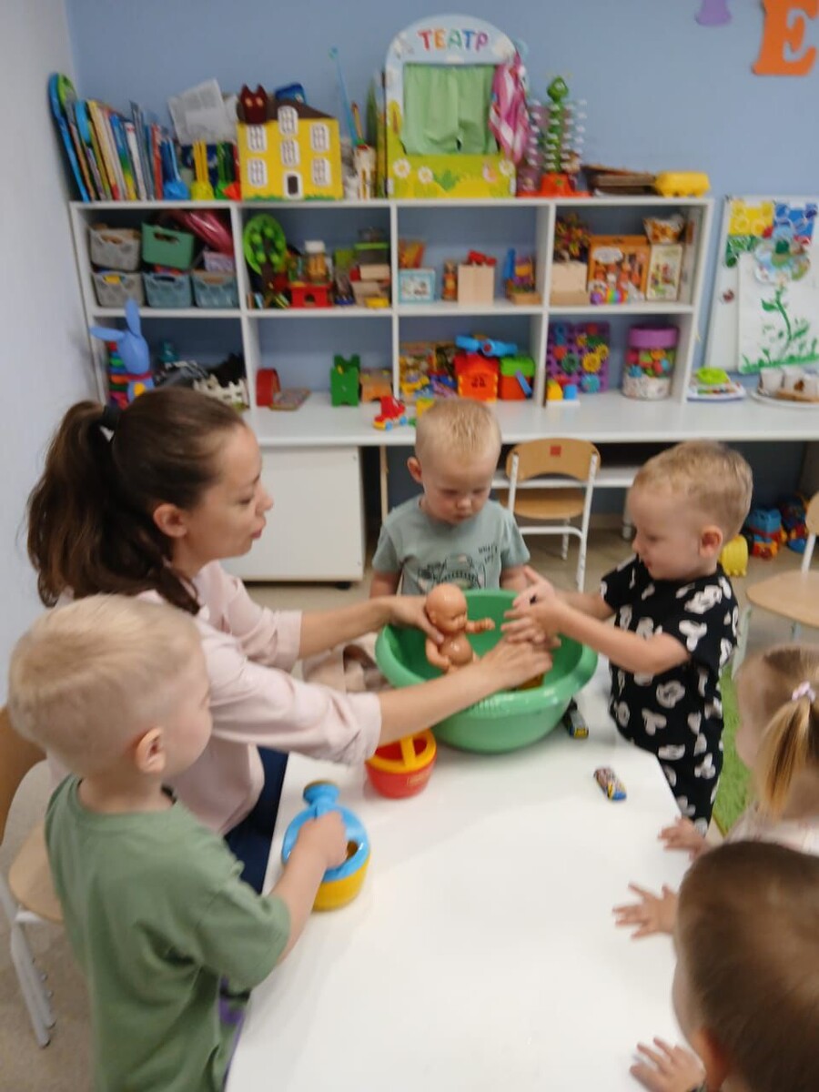 На фото и видео Татьяна Игоревна с ребятами ясельной группы «Крепыши» филиал на Краснодарской учатся купать куклу (обучение сюжетной игре), подбираем температуру воды для купания (через собственный сенсорный опыт дети выбирают для куклы, то что им самим приятно), развиваем эмоциональный интеллект, тренируем эмпатию.