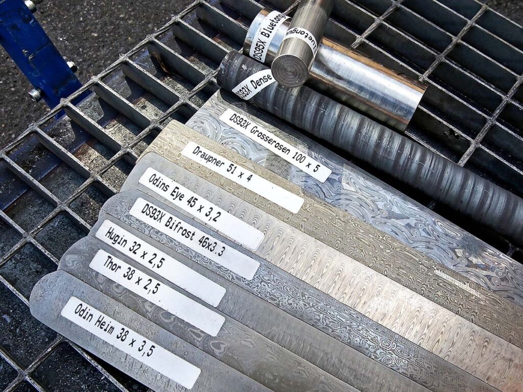 Сталь DS93X, занимающая четвёртое место снизу в форме бруска, представляет собой классический сплав Damasteel. Она сочетает в себе отличные эксплуатационные качества и привлекательный внешний вид.

«Для нас важнее расширять ассортимент, а не экспериментировать с новыми комбинациями сталей», — подчеркнул Пер Ярбелиус. Другие узоры в брусках — это типичные образцы, которые можно ожидать от шведского производителя стали.