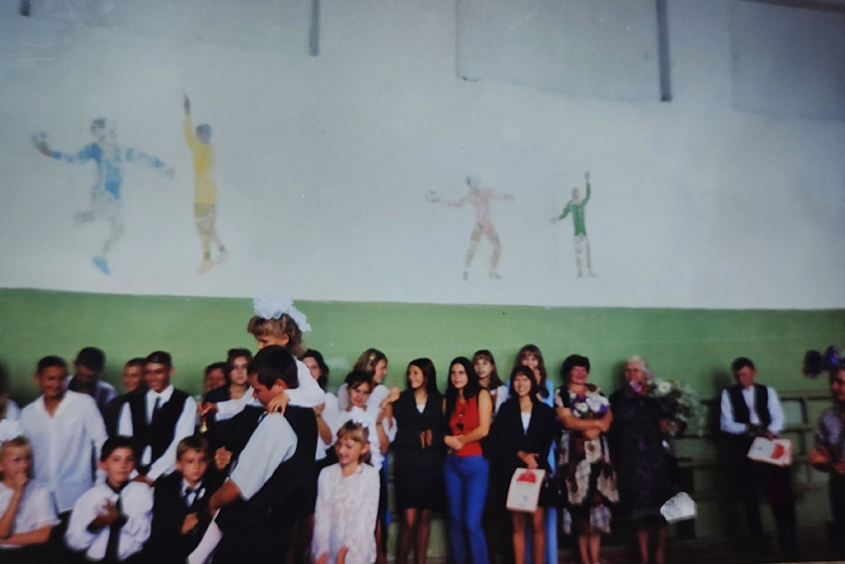 1 сентября 1 класса. Времена, когда детей в школе было ещё много и линейки проходили в спортзале. Девочка, которую несут на плече — я :) 