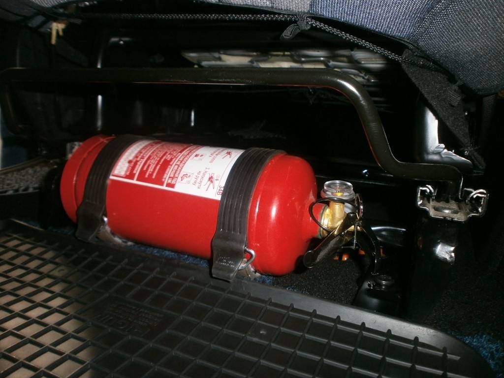 Крепление огнетушителя кронштейном с фиксирующими лентами под сидением