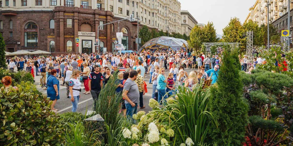 Счастливые люди гуляют по украшенной Тверской улице на День города в Москве.