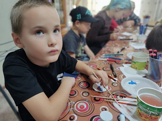 Мальчик держит в руке кисть для акварели