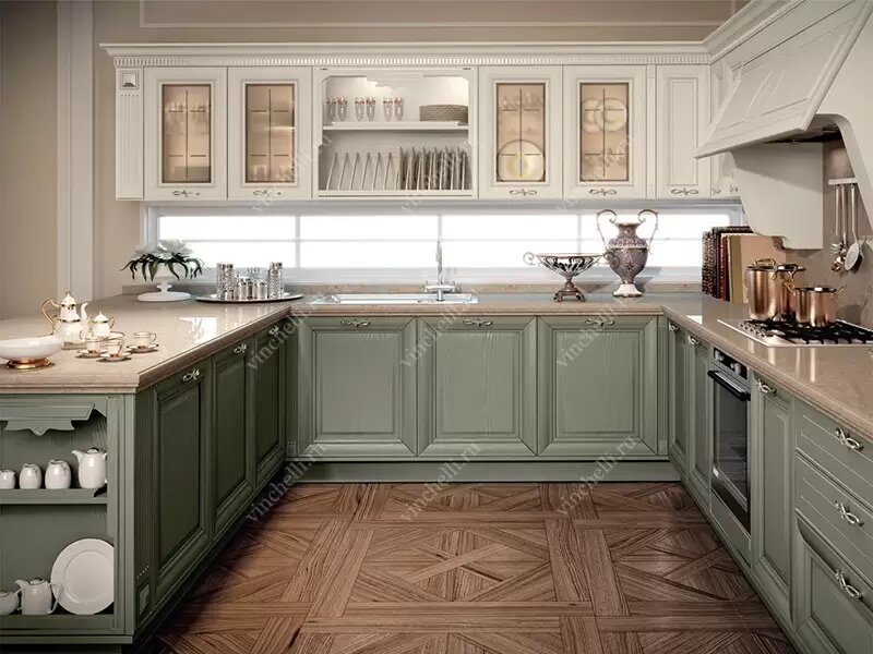 Кухня в стиле Прованс с характерным сочетанием светлых верхних шкафов и нижних фасадов оливкового цвета. Изящные молдинги, стеклянные витрины, керамическая посуда и тёплый свет создают уютную и элегантную атмосферу.