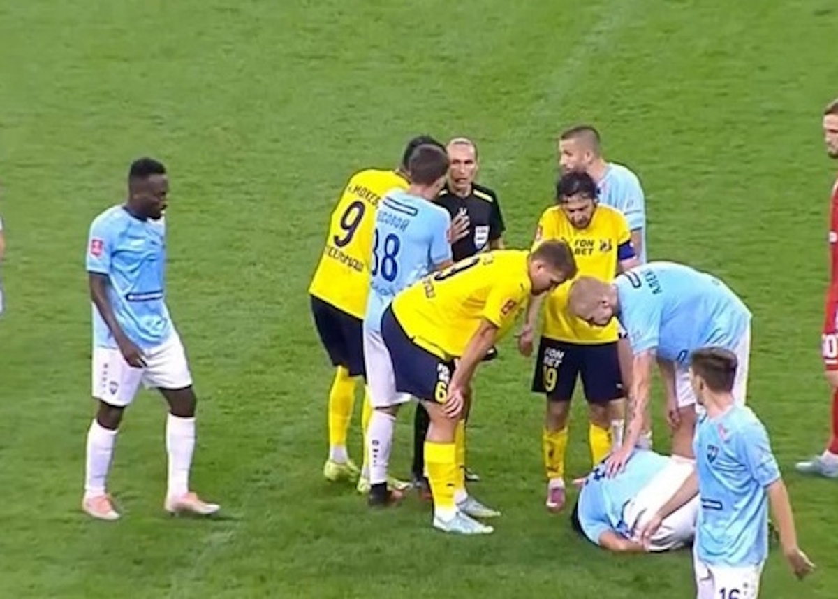 И за грудь её хватает...