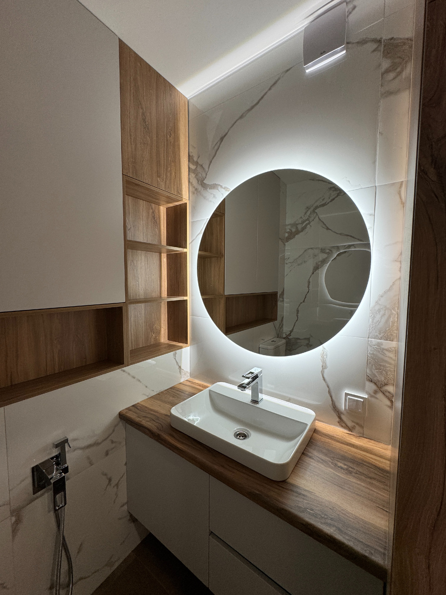 Санузел с подсветкой зеркала и тёплыми оттенками плитки