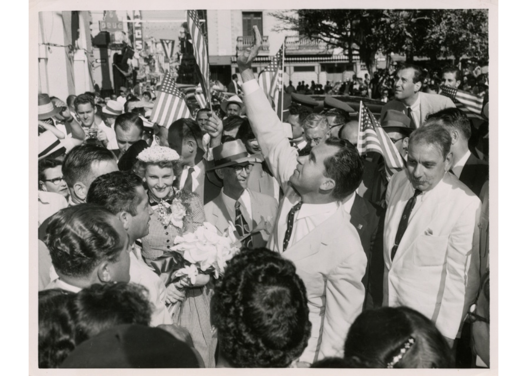 Несмотря на неопределённый статус Пуэрто-Рико в американской политике, политики США регулярно посещали остров. На этом фото вице-президент Ричард Никсон (в центре) машет прохожим, выглядывающим из окон, после своего прибытия в Сан-Хуан.