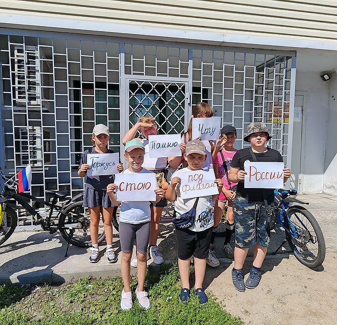 Дети держат в руках листы со словами уважения к Родине