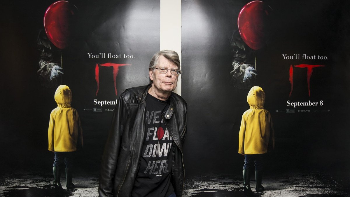 Писатель Стивен Кинг на фоне постера к фильму ужасов "Оно" (2017)