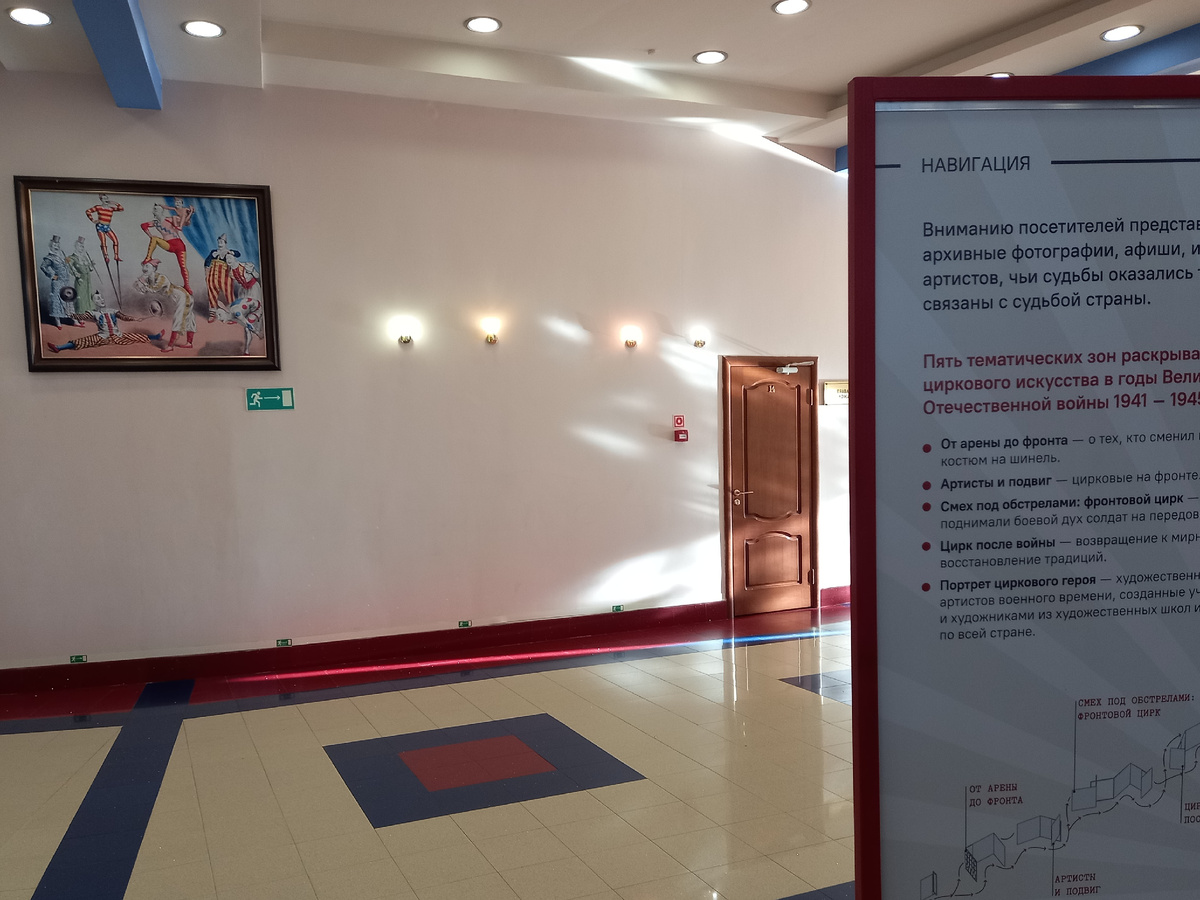 Один из стендов экспозиции и картина на стене. Коридоры пронизаны лучами солнца.