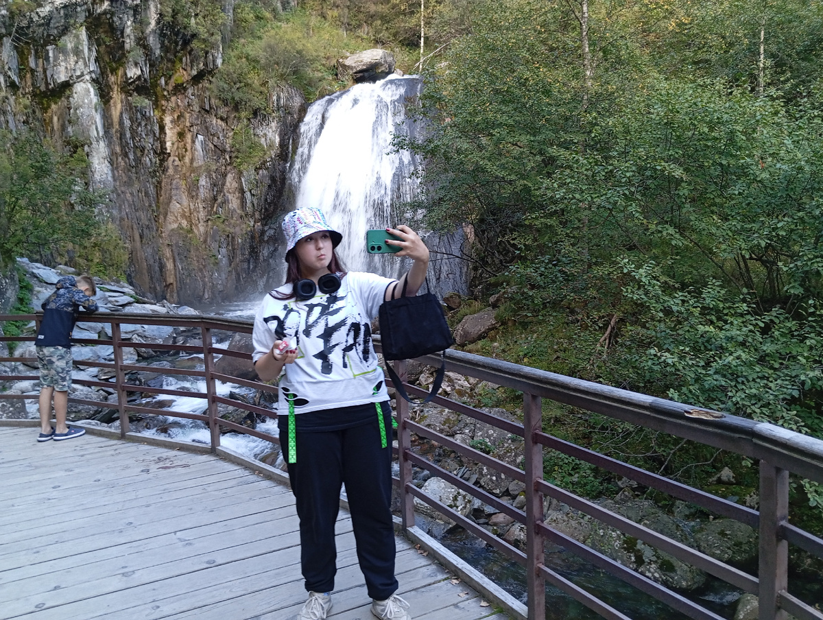 Туристка Алтайтурмаркет на фоне водопада Корбу