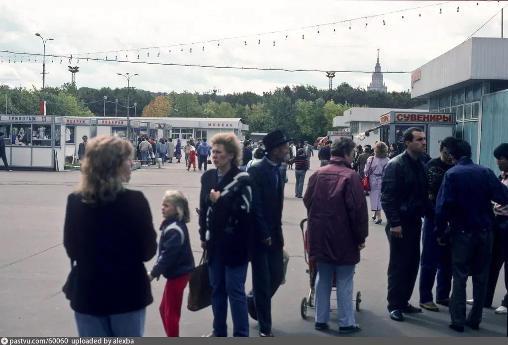 Стоит сказать, что ярмарка в Лужниках существовала ещё в советские времена (примерно с 1960-х годов). Там продавали разные товары, в основном дефицит. Павильоны принадлежали крупным столичным универмагам. То есть в принципе это не то же самое, что обычный рынок. Но располагалось всё там же, где потом возвели крытые павильоны "Лужников". Видимо, поэтому на входе в нулевых красовалась табличка "Ярмарка". Этот снимок сделан в 1991 году. С сайта www.pastvu.com.