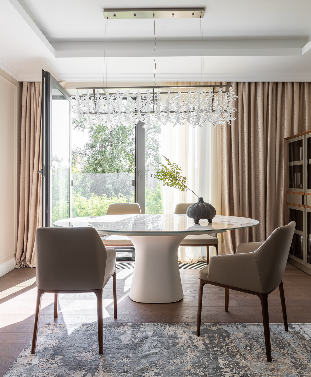 Столовая у панорамного окна наполнена светом и видом на сад, создавая атмосферу элегантных ужинов.