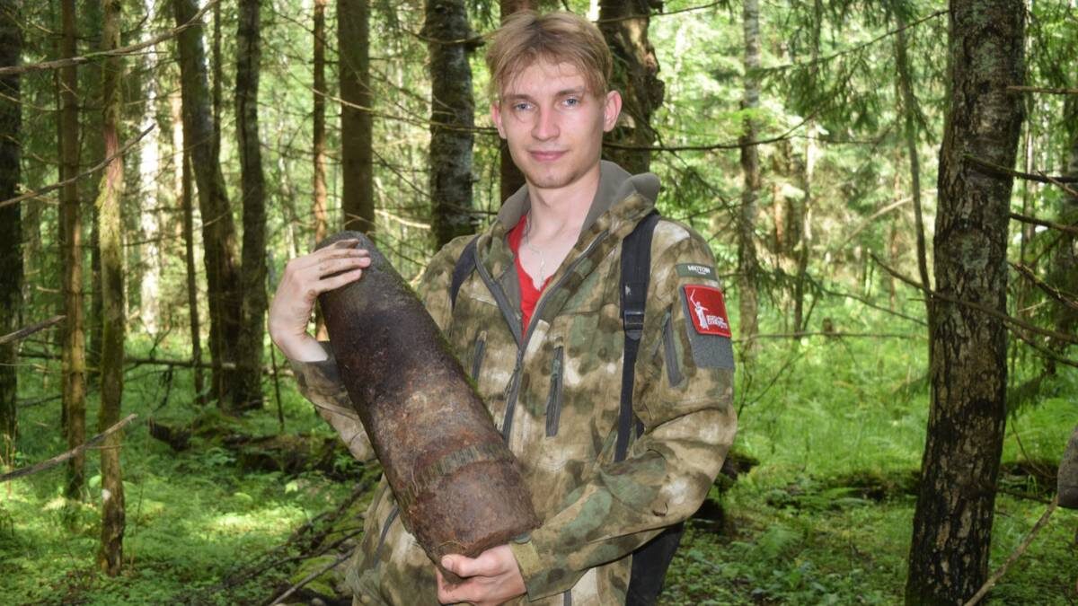   Доброволец из Москвы Даниил Шамин держит в руках найденный в лесу подо Ржевом корпус артиллерийского снаряда / Фото: Диана Прохоренко