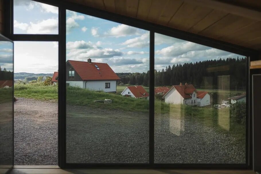 Большой панорамный оконный проём с тонированным стеклом. Тонировка снижает яркость солнечного света, защищает интерьер от перегрева и добавляет уюта дому.