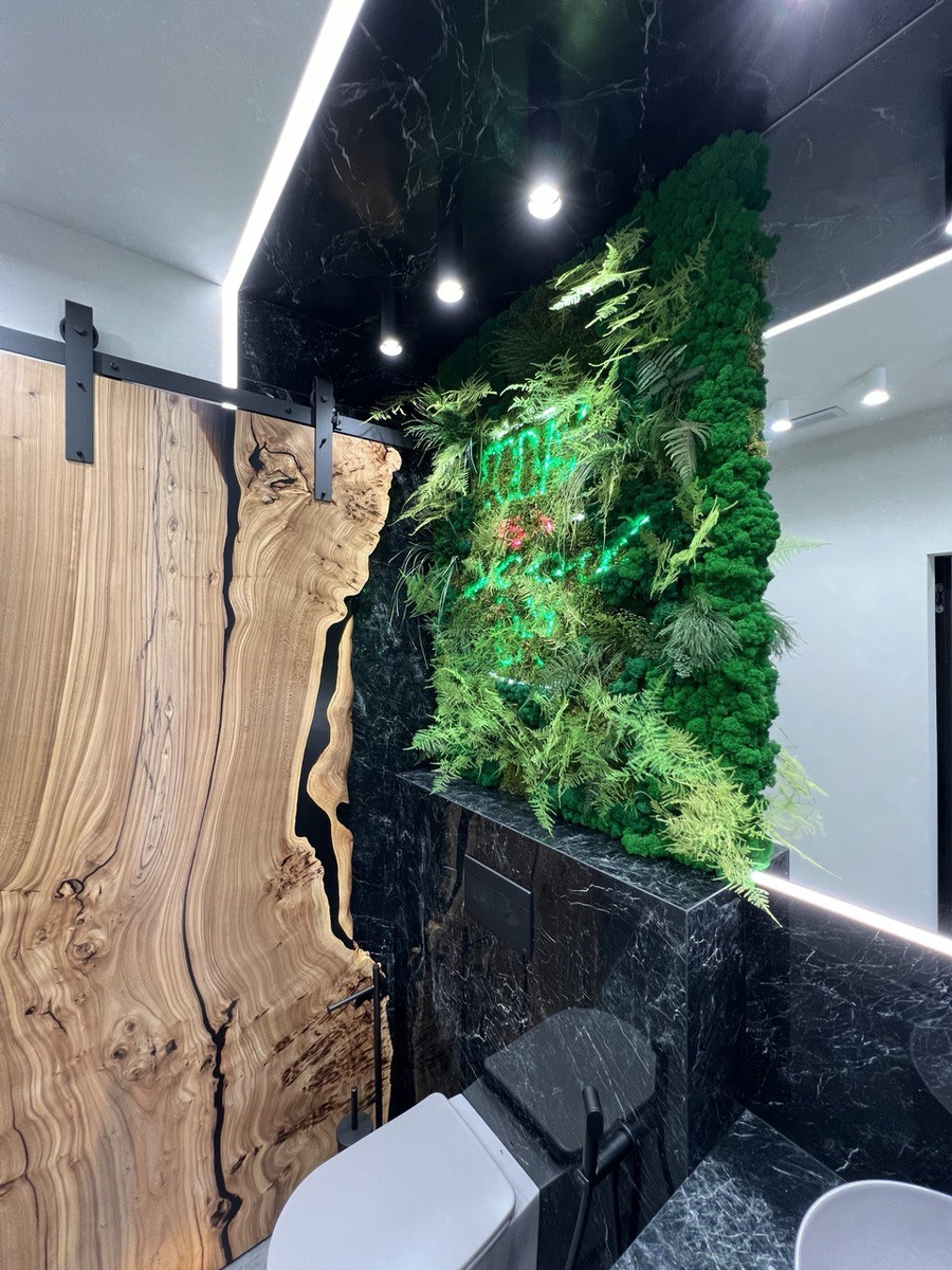 Санузел с зелёной панелью из стабилизированного мха — пример интеграции мха в ремонт под ключ: дерево, мрамор и натуральная текстура.