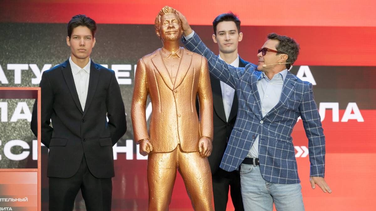    Павел Деревянко на аукционе со статуей из сериала «Беспринципные» / Фото: Дмитрий Дубинский / Вечерняя Москва