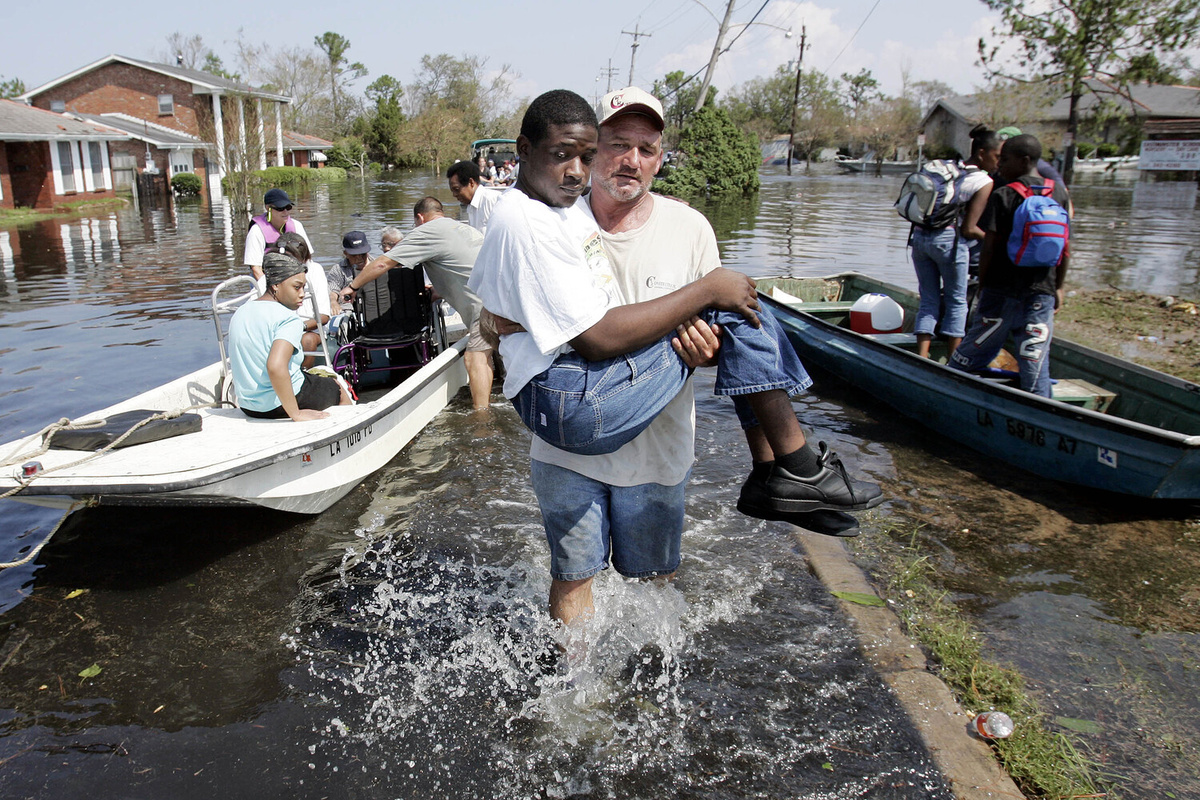 Волонтеры помогают местным жителям пройти в безопасное место из затопленного района на восточной стороне Нового Орлеана, США, 31 августа 2005 года ©Eric Gay/AP 