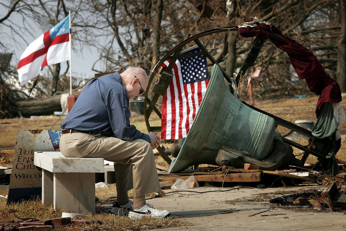 Прихожанин епископальной церкви Искупителя Джуниус Коттен после окончания службы сидит у руин колокольни, разрушенной ураганом «Катрина» в Билокси, штат Миссисипи, 4 сентября 2005 года ©Win McNamee/Getty Images  📷