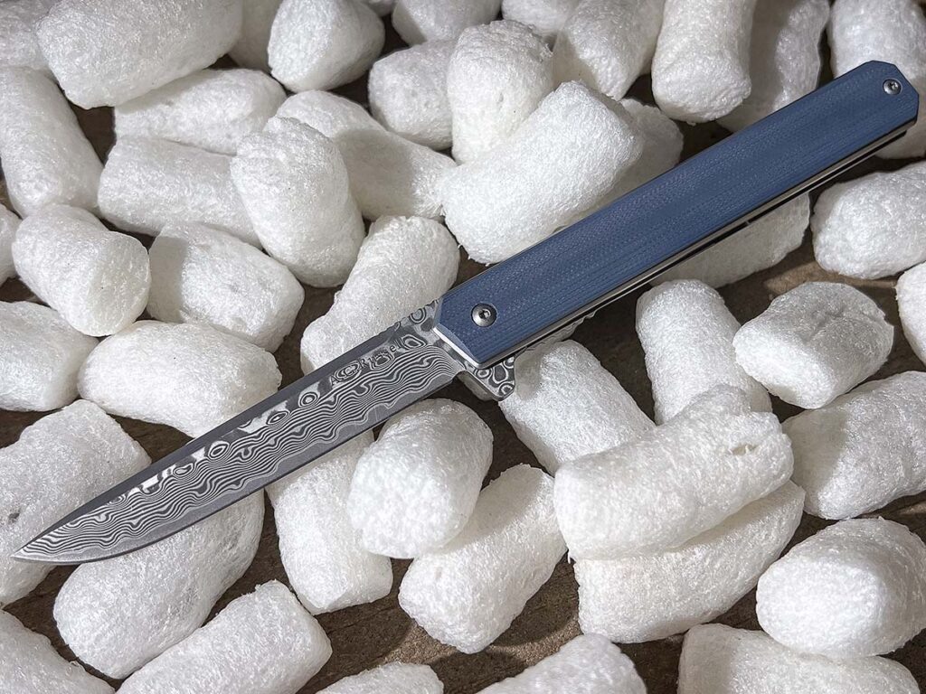 Трёхдюймовое лезвие от A.G. Russell с заострённым кончиком — это уникальный сплав дамаска и сан-мая. Оно изготовлено из сердечника из стали 9Cr13MoV, который покрыт с обеих сторон дамасской сталью.