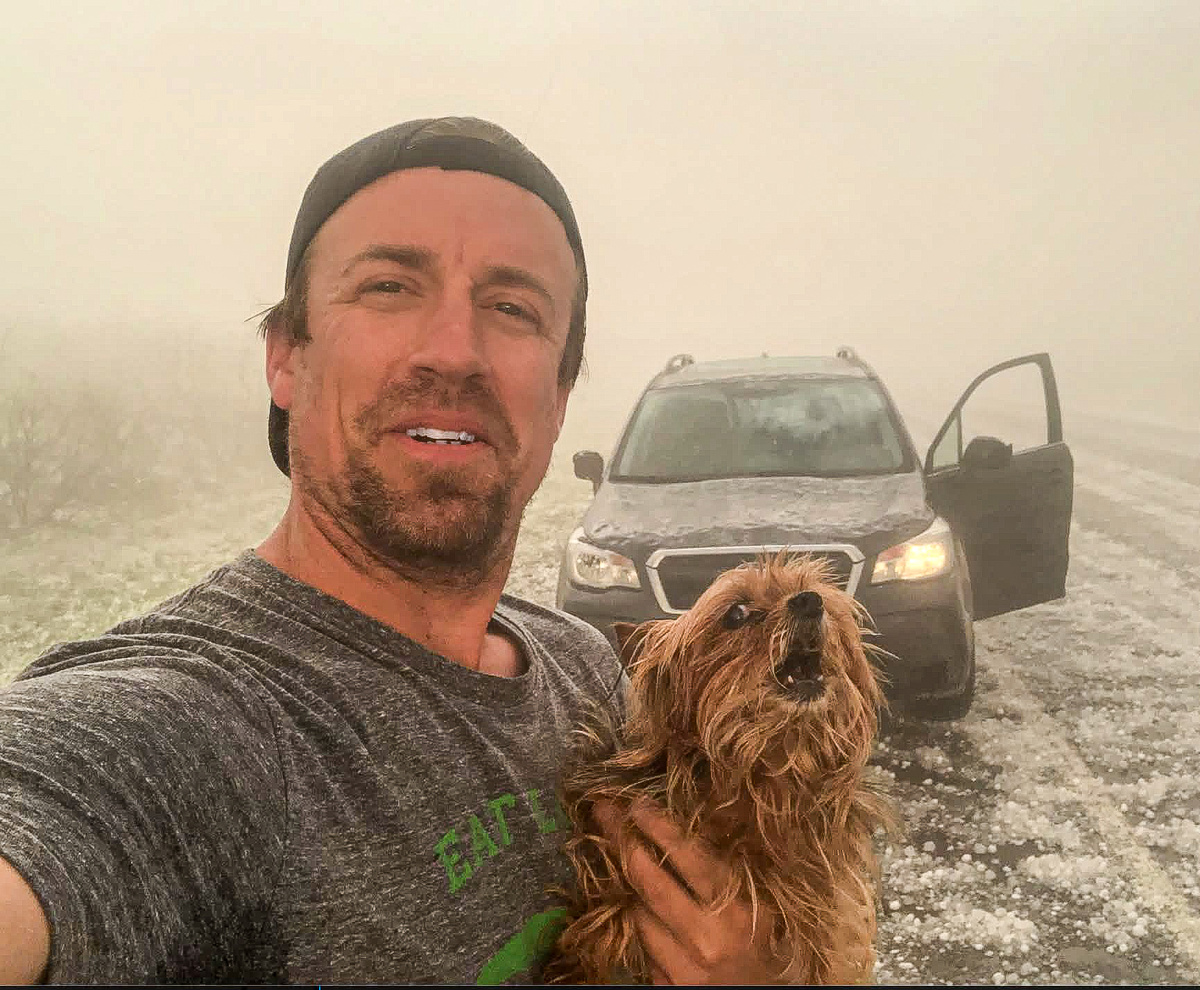 Рид Тиммер, известный охотник за торнадо, делающий селфи с собакой на фоне автомобиля Subaru Forester, который используется для охоты за торнадо.