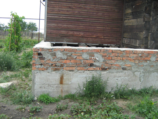 Дом с демонтированной пристройкой и блоками для нового фундамента.