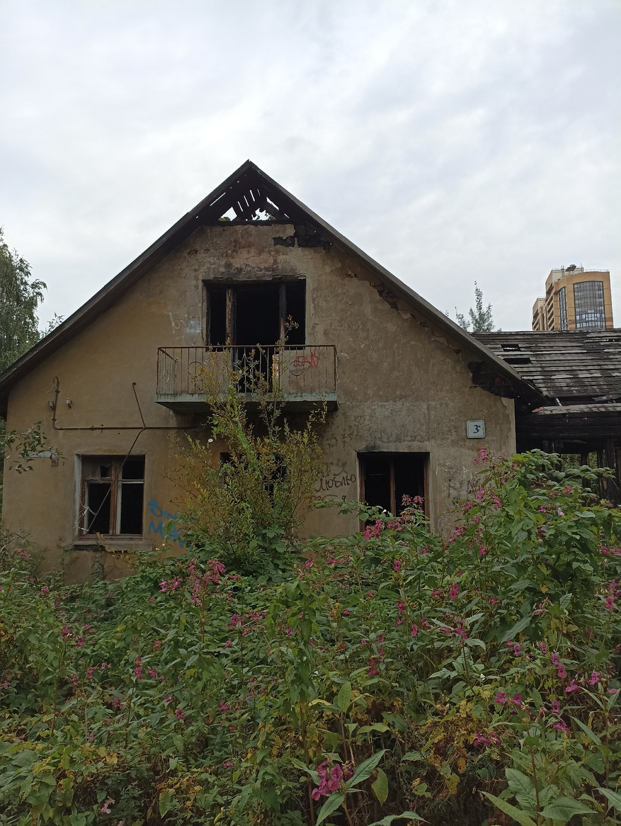 Старый заброшенный дом, а за ним небоскрёб