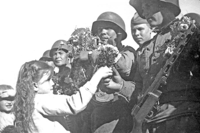 Сентябрь 1945 г. Жители г. Александровска встречают воинов 179-го стрелкового полка 79-й стрелковой дивизии, участвовавших в Южно-Сахалинской наступательной операции и прибывших после боёв к месту постоянной дислокации. Во время Южно-Сахалинской наступательной операции 179-й стрелковый полк (командир подполковник Е. А. Кудрявцев) участвовал в овладении Харамитогским укреплённым районом, железнодорожной станцией и посёлком Котон (ныне Победино), брал населённые пункты Сисука и Найро (ныне Леонидово и Гастелло). Указом Президиума Верховного Совета СССР от 14 сентября 1945 года за образцовое выполнение заданий командования в боях против японских войск и проявленные при этом доблесть и мужество 179-й стрелковый полк награждён орденом Красного Знамени. Фото старшего сержанта Григория Соколова, фотографа политотдела 79-й стрелковой дивизии, впоследствии фотокорреспондента газеты «Советский Сахалин».