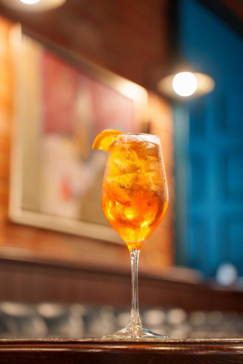 В гастробаре Busby бармены чтут традиции и предлагают классический коктейль «Апероль Спритц» с тем самым традиционным составом: апероль, просекко, содовая, долька апельсина и лёд.