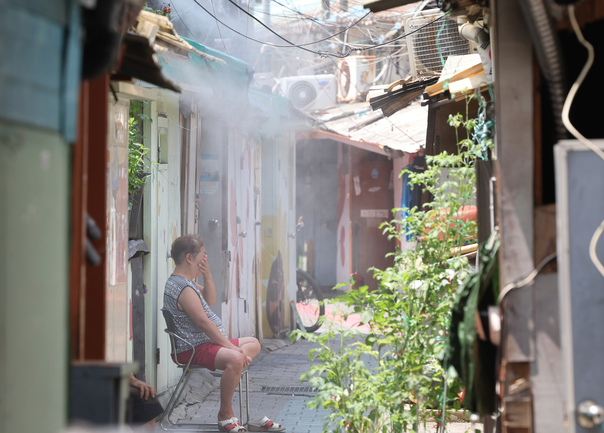 Некий местный житель сидит в одном из переулков «тёкбанчхона» в округе Ёндынпхо-гу на западе Сеула, 9 июля. Тёкбанчхон — это группа деревень с однокомнатными квартирами, в основном состоящих из пожилых людей из малообеспеченных семей (Ренхап)